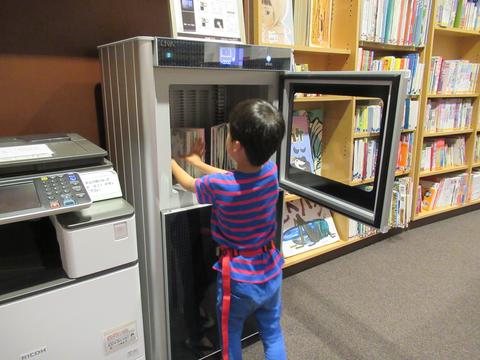 男の子が図書除菌機に本を入れている写真