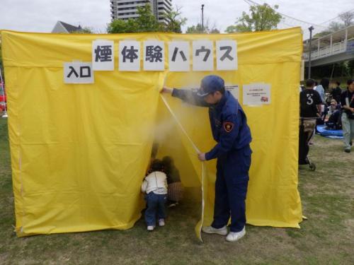 団員による煙体験ハウス案内