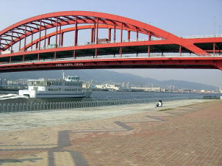 北公園から見た赤い神戸大橋の写真、橋の下を船が走っている